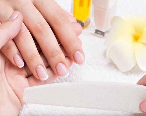 Woman in a nail salon receiving manicure Woman in a nail salon receiving manicure by a beautician. Beauty treatment concept.